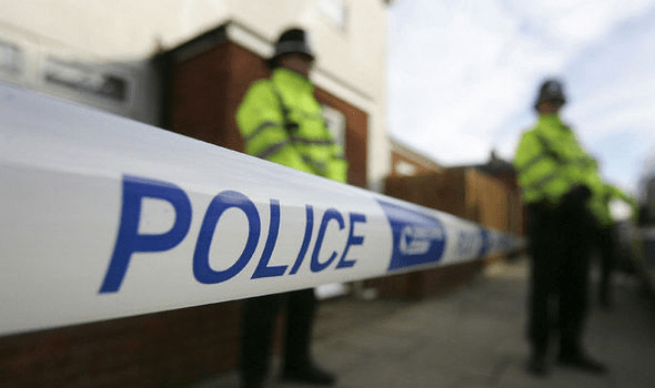 Police sergeant standing behind police tape with another officer